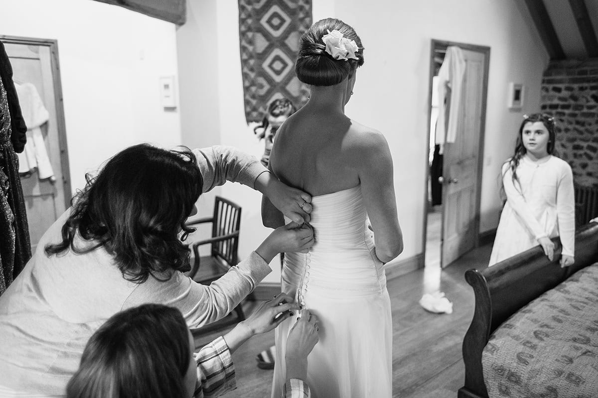 the bridesmaids help dress the bride