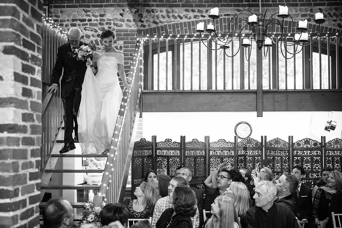 the bride and her father walk down the stairs in chaucer barn