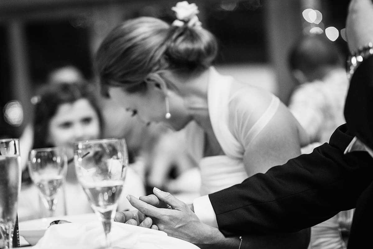 the bride and groom hold hands during the speech