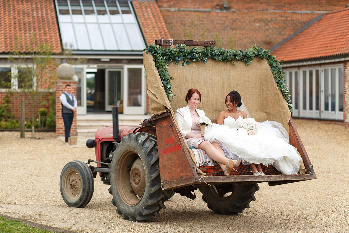 the bride and her maid of honour in the back of the tractor