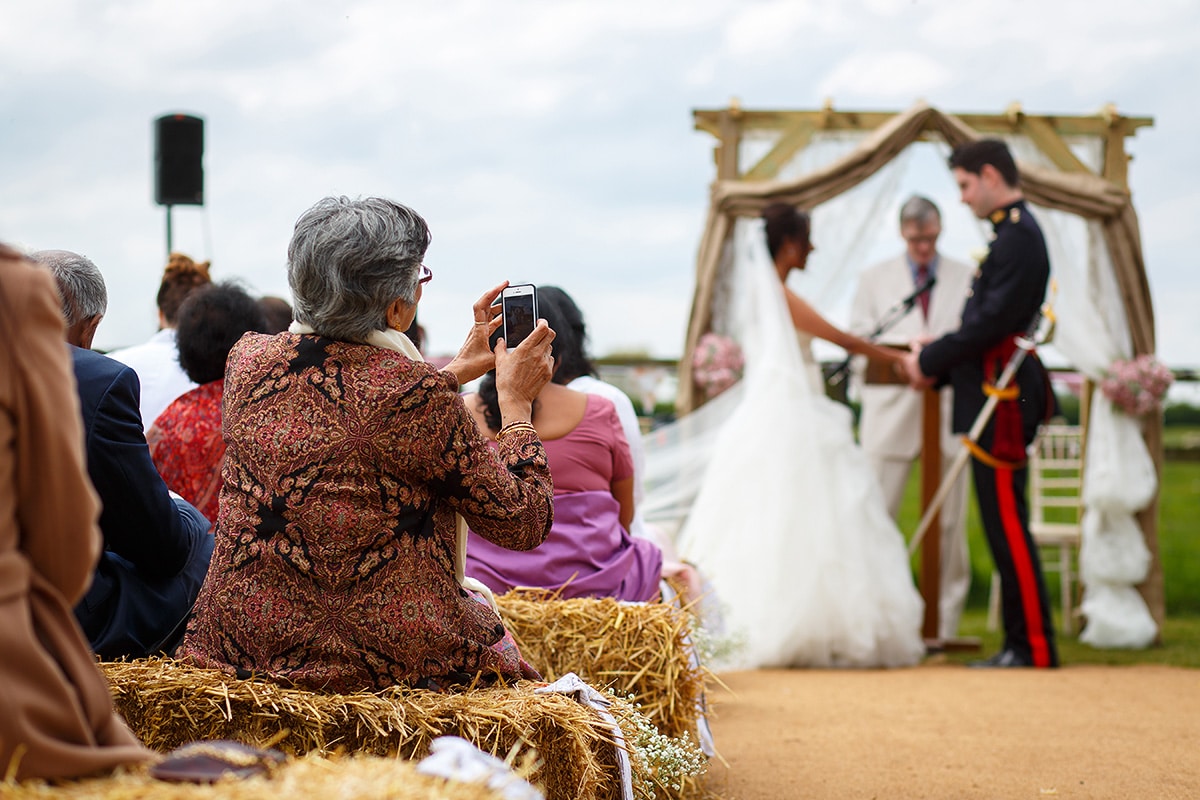 a guest takes a photo during the outdoor ceremony