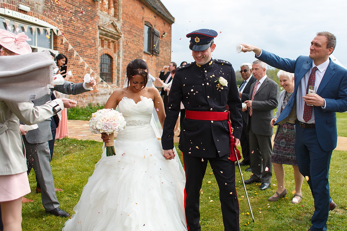 the bride and groom walk through the confetti