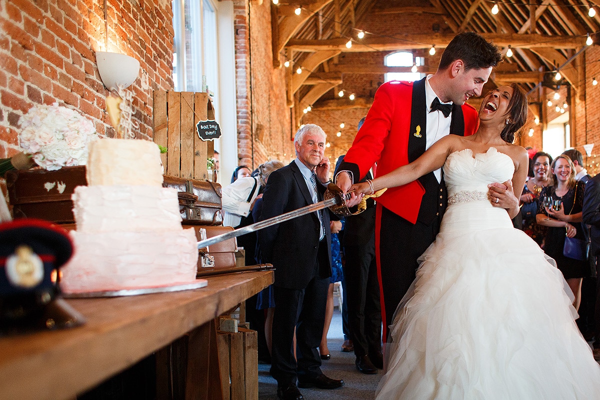 bride and groom cut the cake inside Godwick Barn