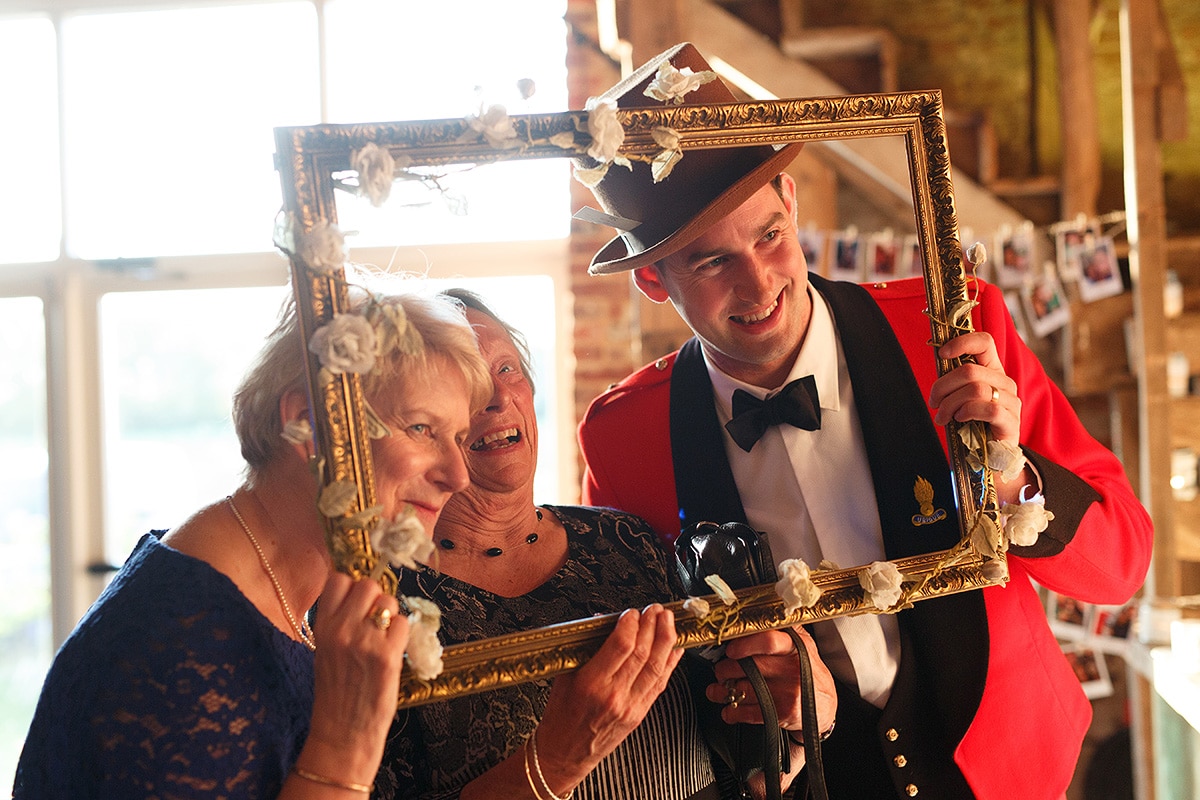 the groom poses in a picture frame with the guests