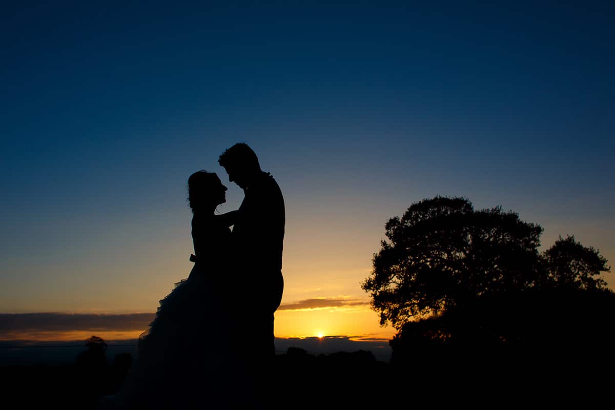 a sunset silhouette of the bride and groom at their godwick barn wedding