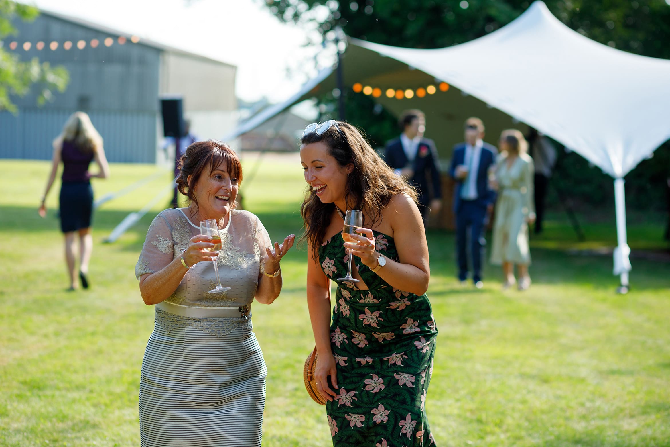the brides mother and a guest walk into the marquee