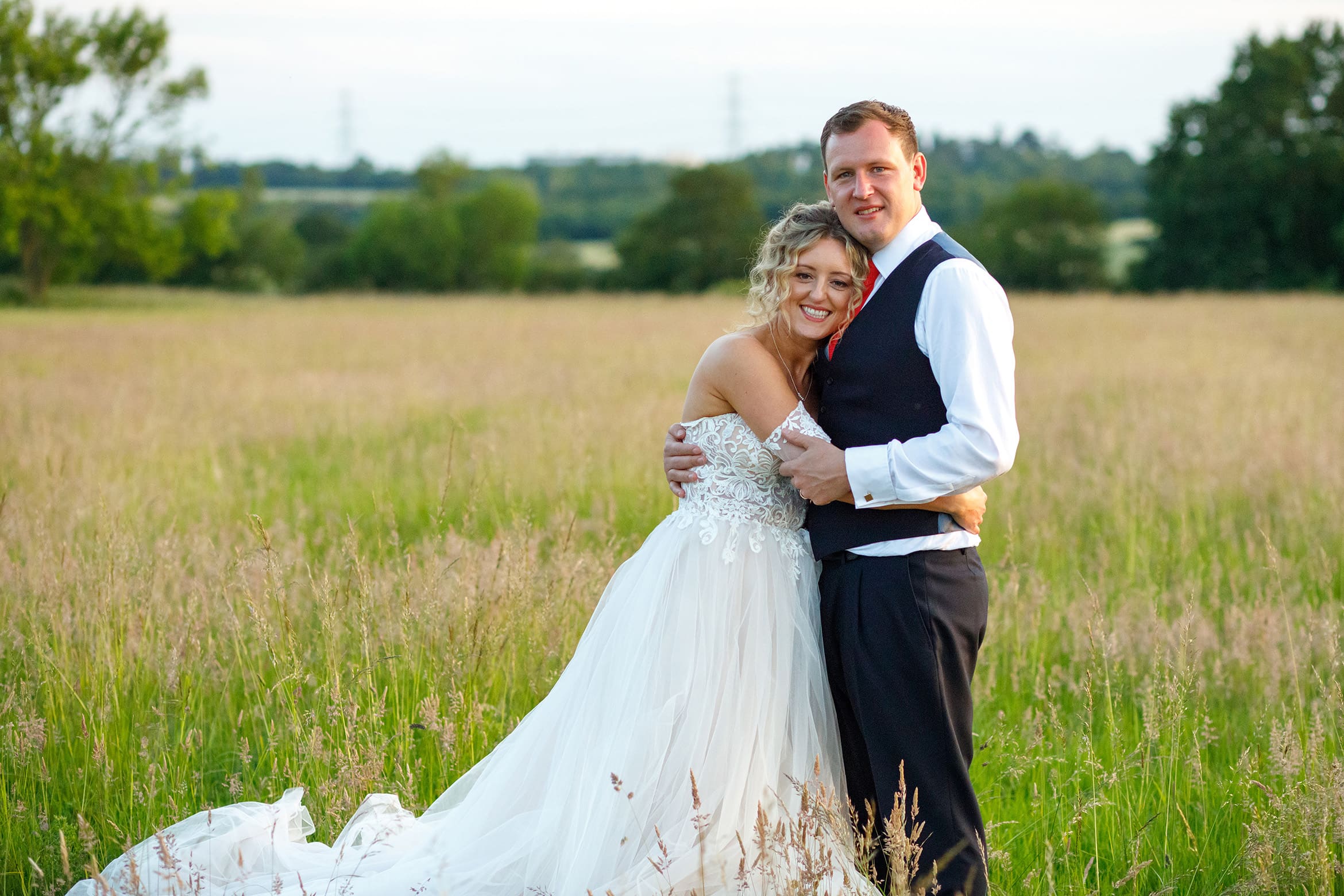 bride and groom pose in a field