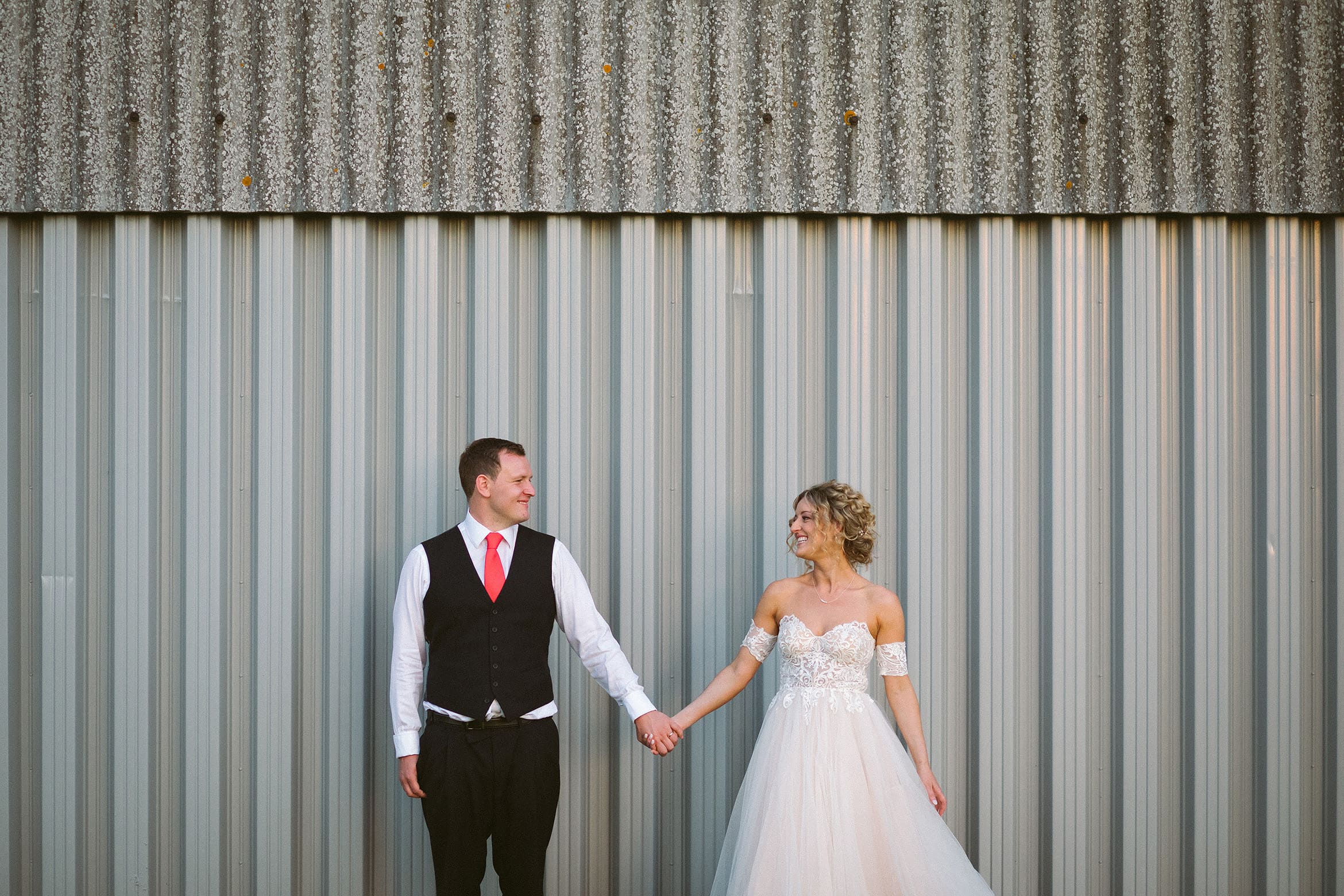 bride and groom pose against a barn