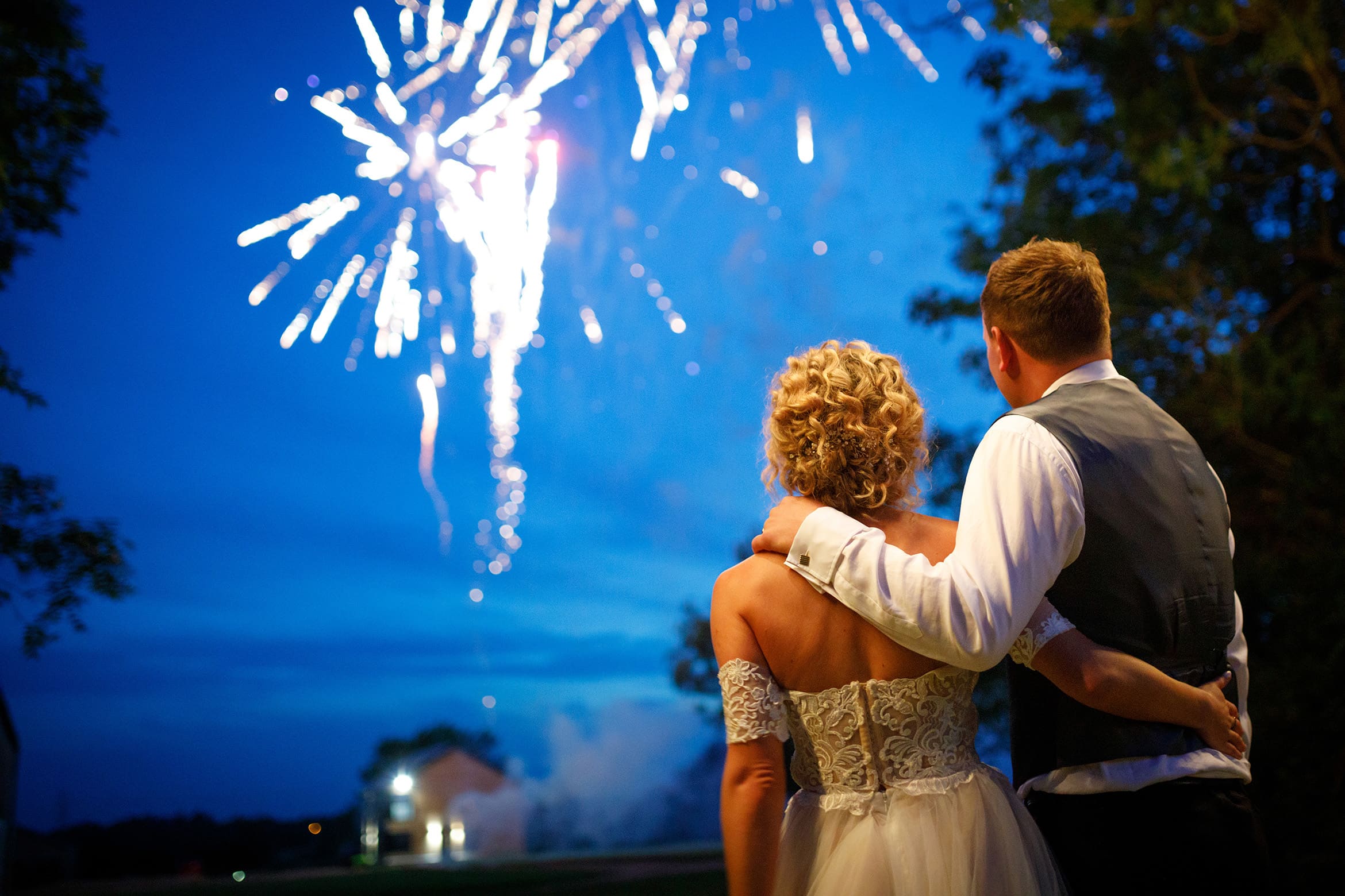 bride and groom embrace in front of the fireworks