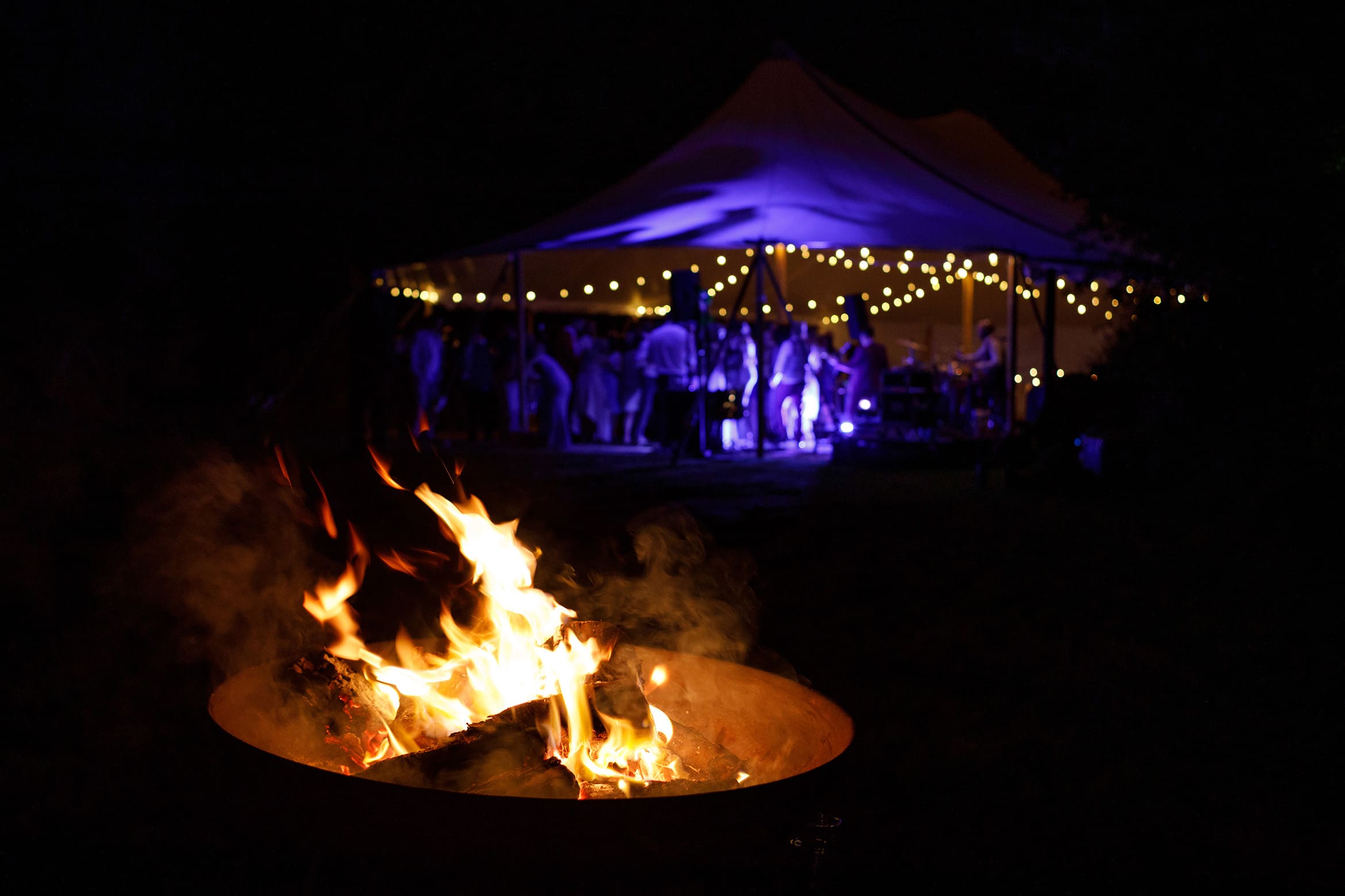 a firepit with the wedding marquee in the background