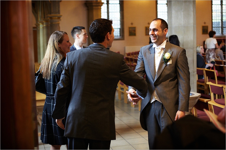 groom greeting guests at the church