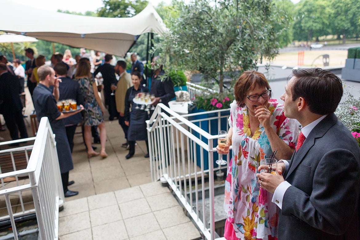 the groom laughs with a guest on the ras balcony