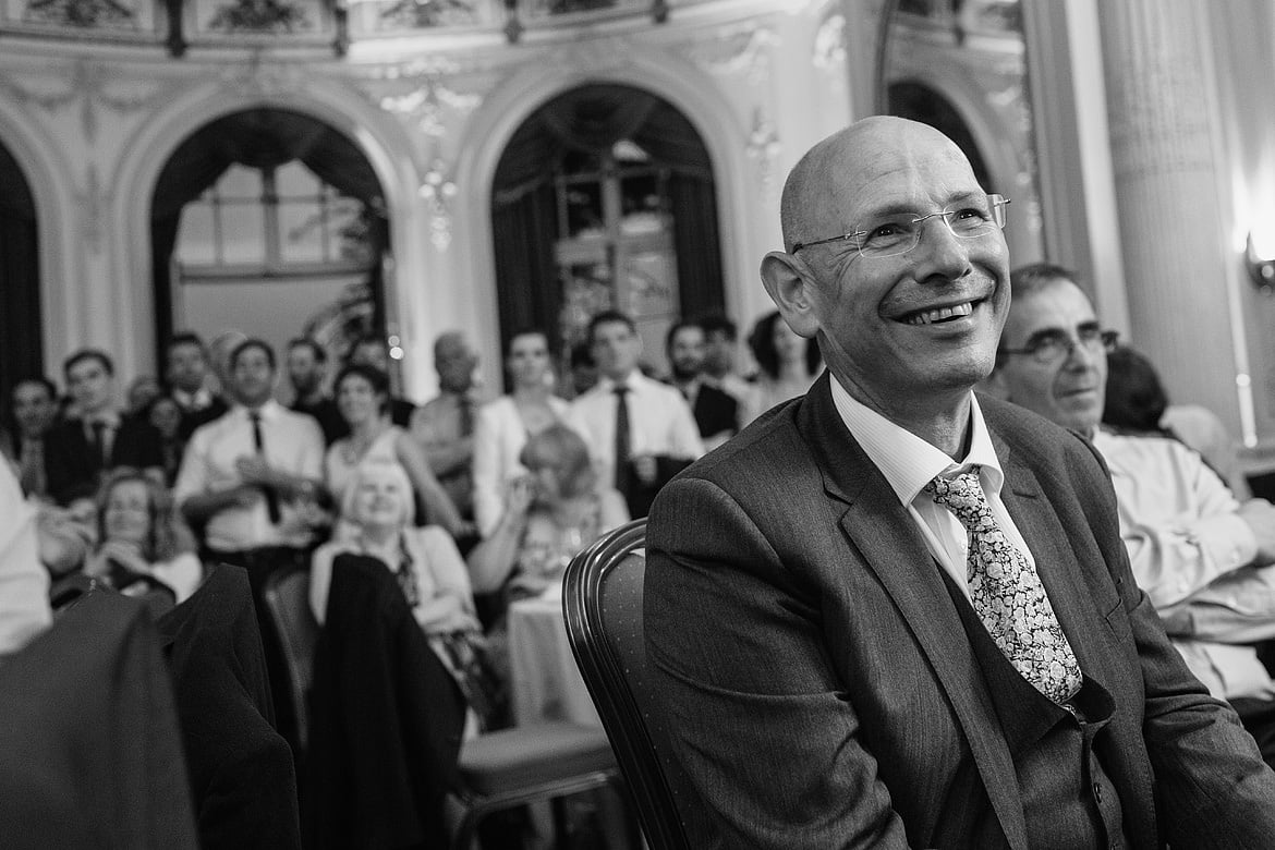 the grooms father listens smiling as the groom speaks