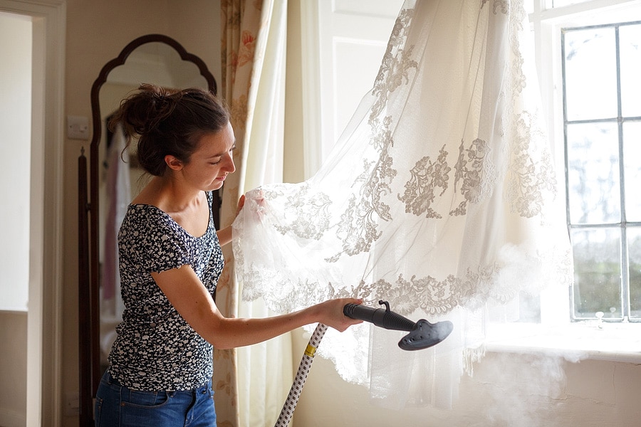 the bride steams the creases from her dress