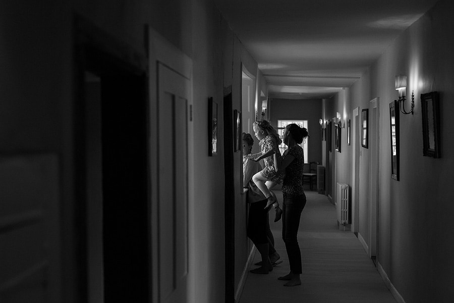 the bride holds the flowergirl up to the window