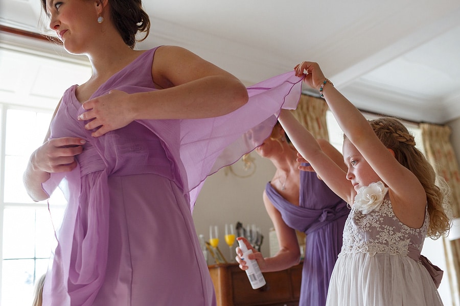a flowergirl holds up a bridesmaids dress