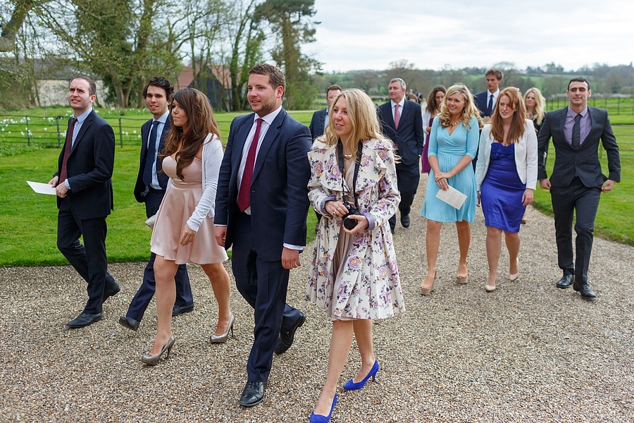 wedding guests walk towards bruisyard hall for the drinks reception