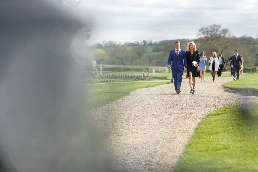 wedding guests walk towards bruisyard hall for the drinks reception