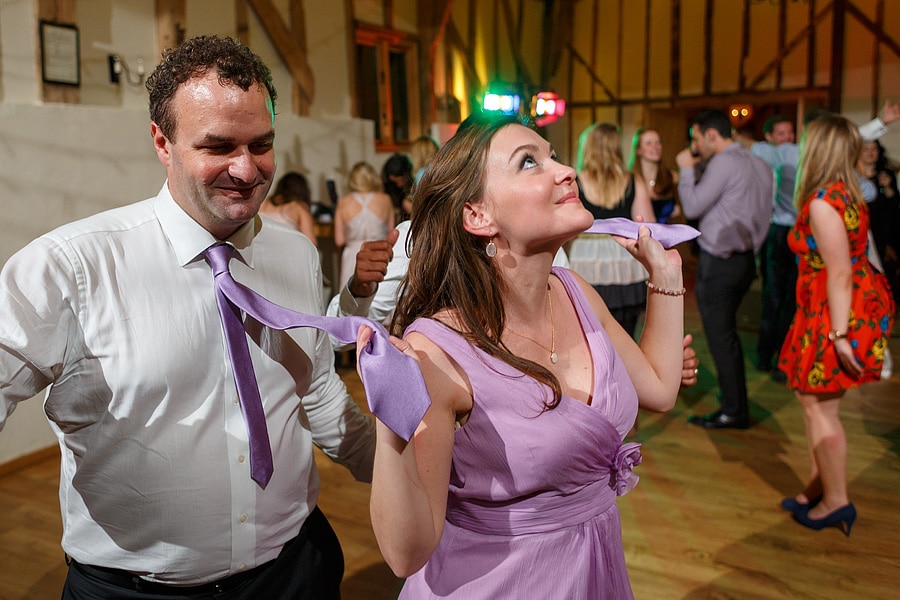 a bridesmaid leads the groom by his tie