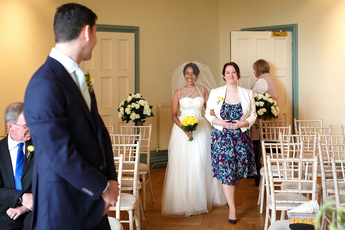 sam walks smiling down the aisle with her maid of honour