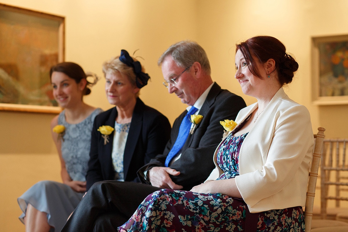 smiling wedding guests as sam and rob sign the marriage register