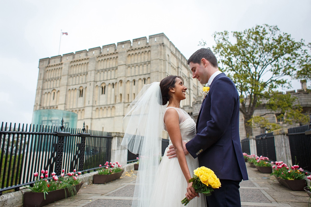 bride and groom gaze into each others eyes in front of norwich castle