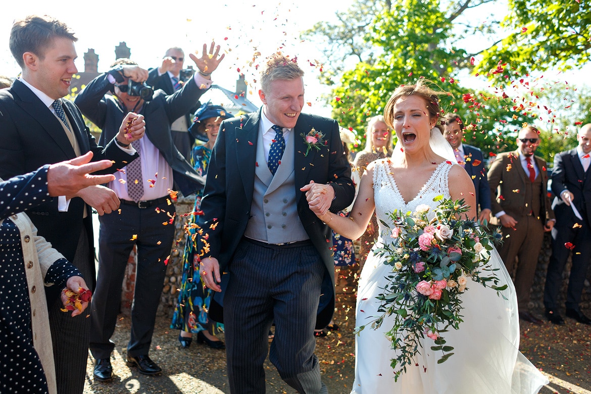 bride and groom run through the confetti outside aldeburgh church