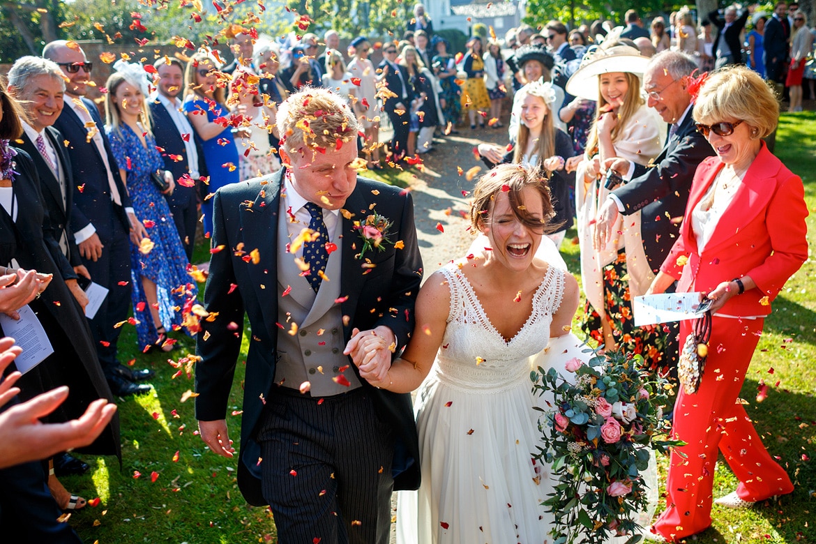 bride and groom run through the confetti outside aldeburgh church