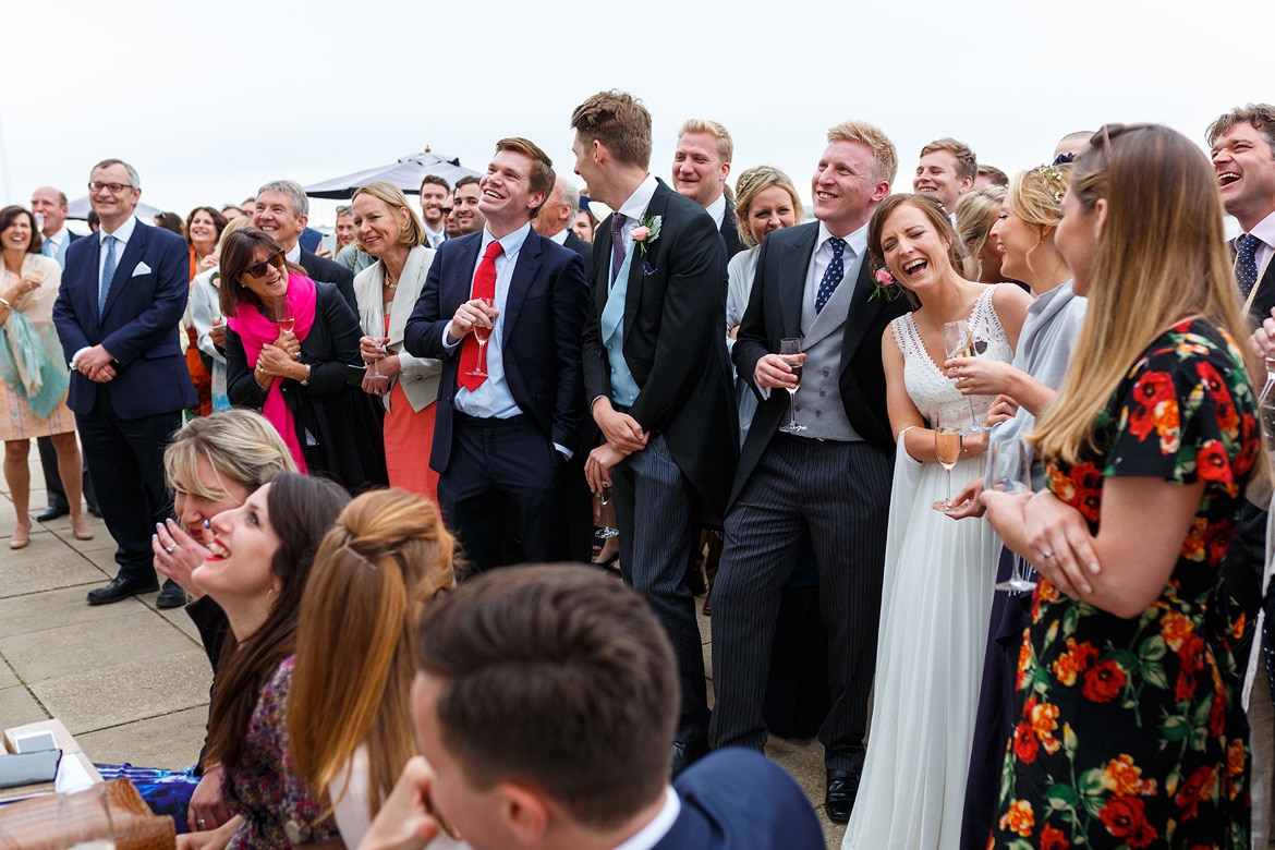 the bride and groom laugh at his brothers speeches