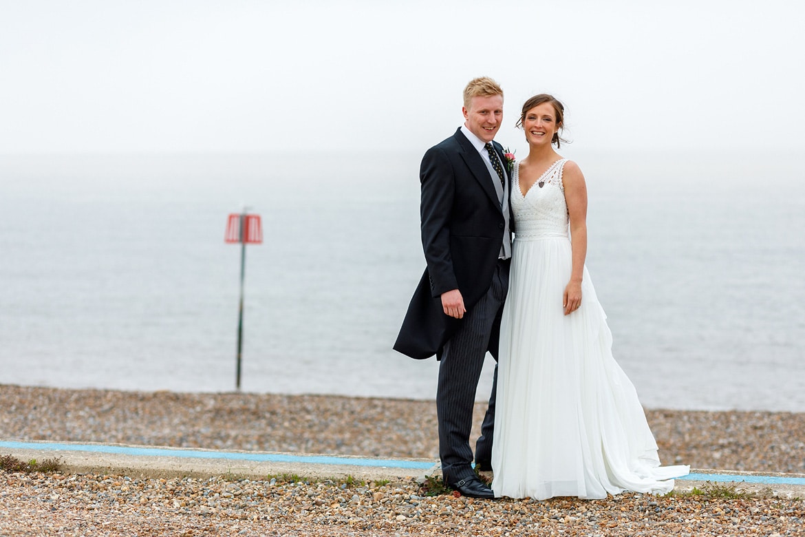 bride and groom pose in front of aldeburgh sea front