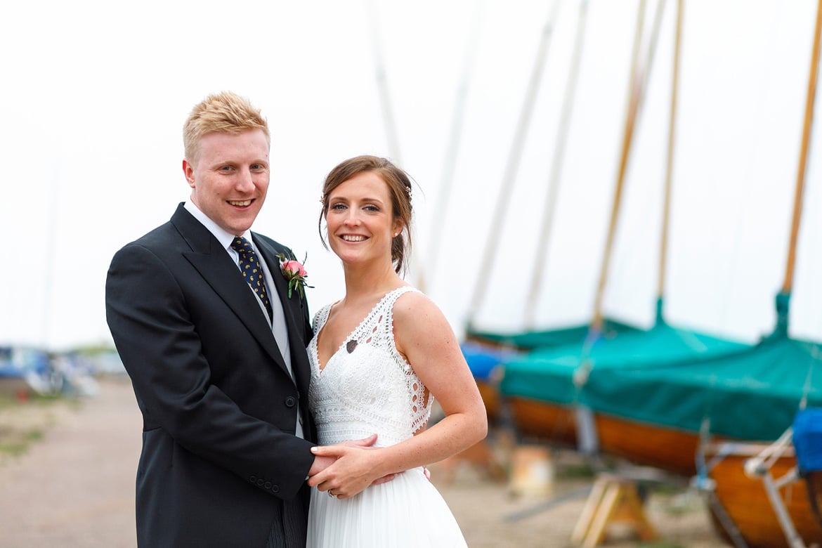 bride and groom pose with yachts in the background