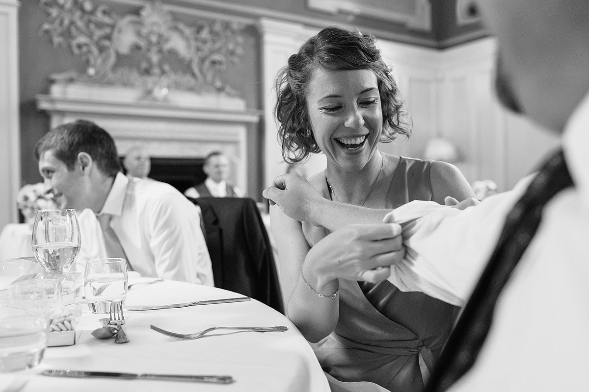 a bridesmaid rolls up her partners sleeve