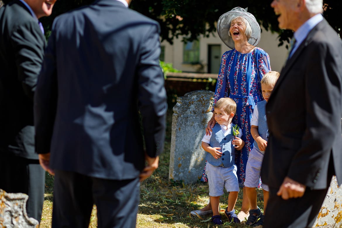 laughing outside an old buckenham church wedding