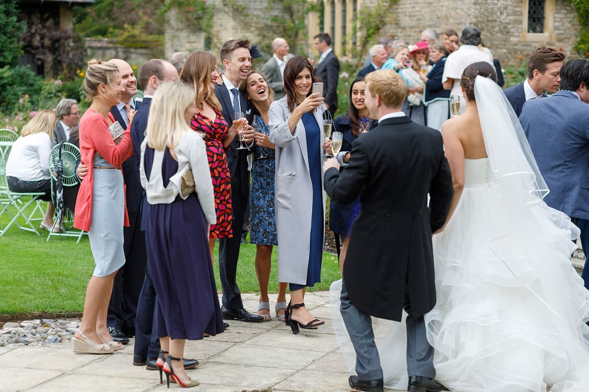 bride and groom pose for photos outside the church at hengrave hall