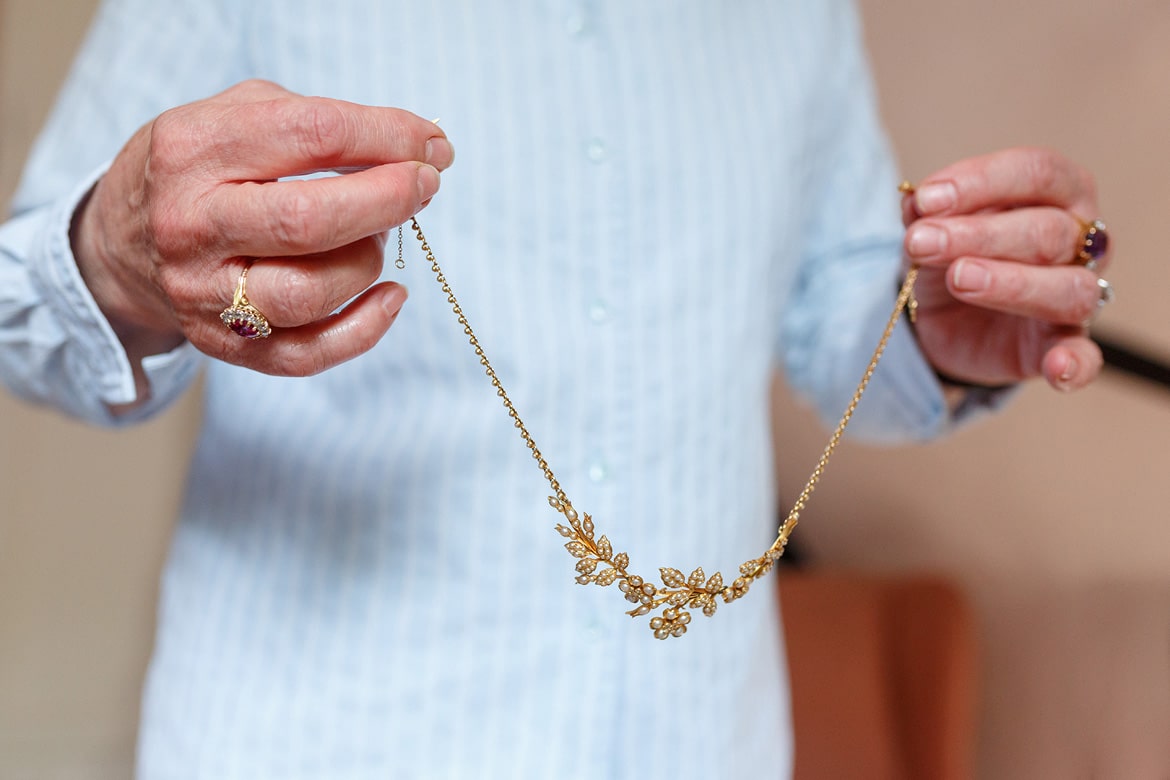 the brides mother holds up a necklace for her daughter