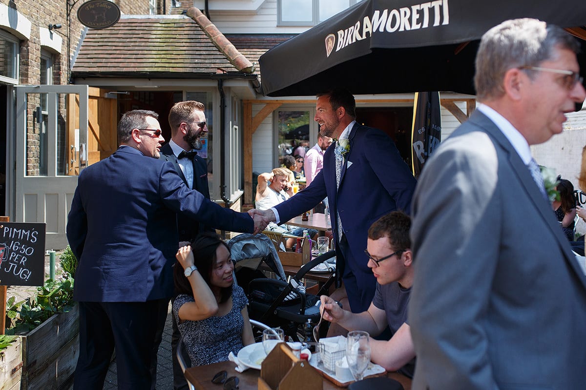 the groom greets ushers at the pub