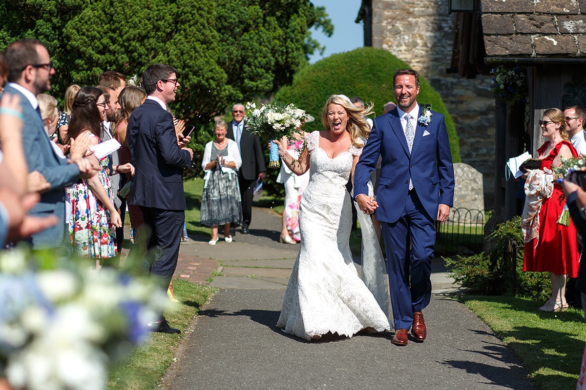 bride and groom walk through the confetti at holy trinity cuckfield