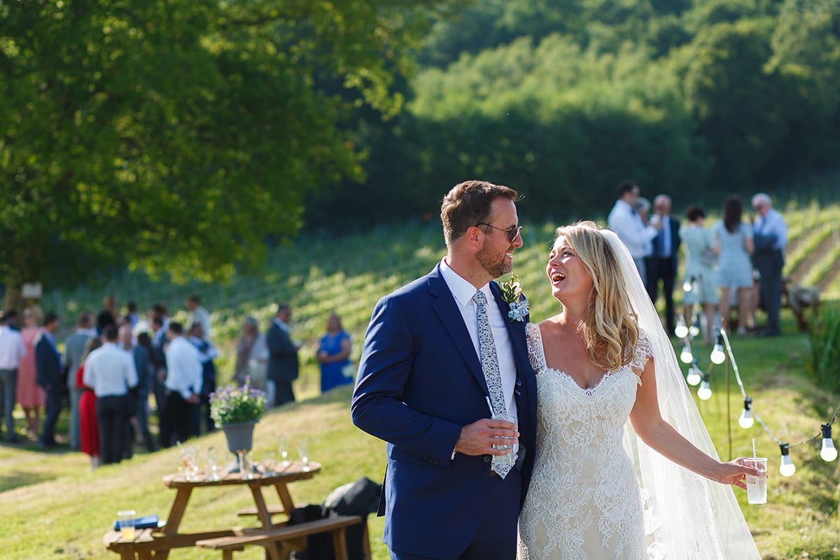 bride and groom laughing together with bluebell vineyard in the background