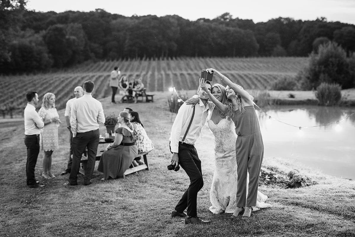 laura takes a selfie with guests with the vineyard in the background