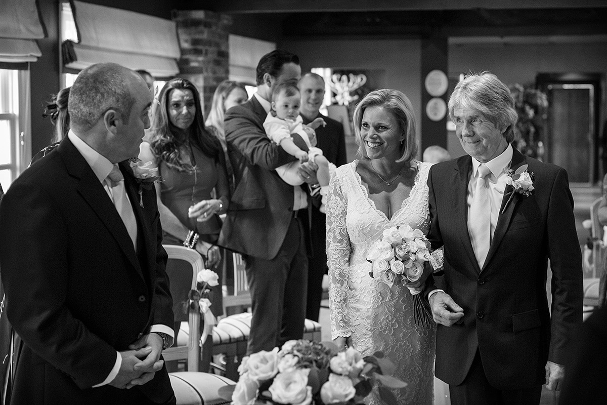 the bride smiles at the groom as she reaches the end of the aisle