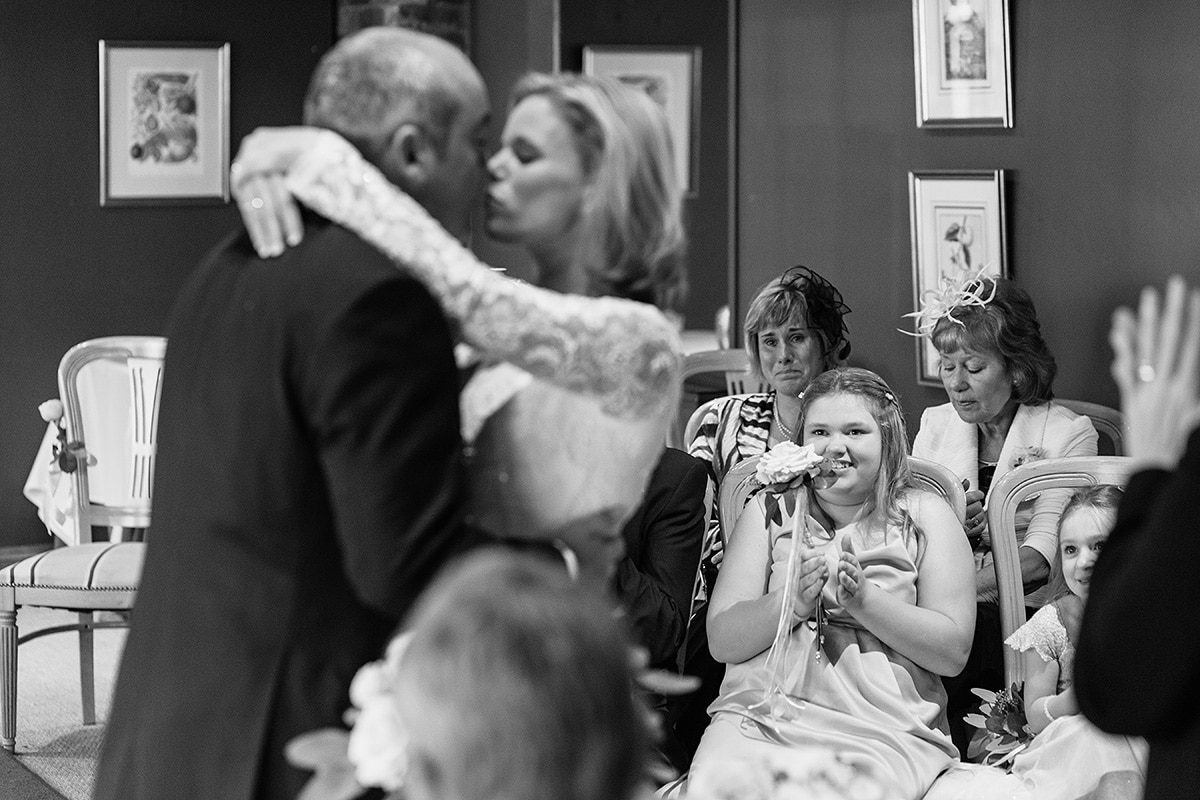 a bridesmaid applauds as the couple kiss