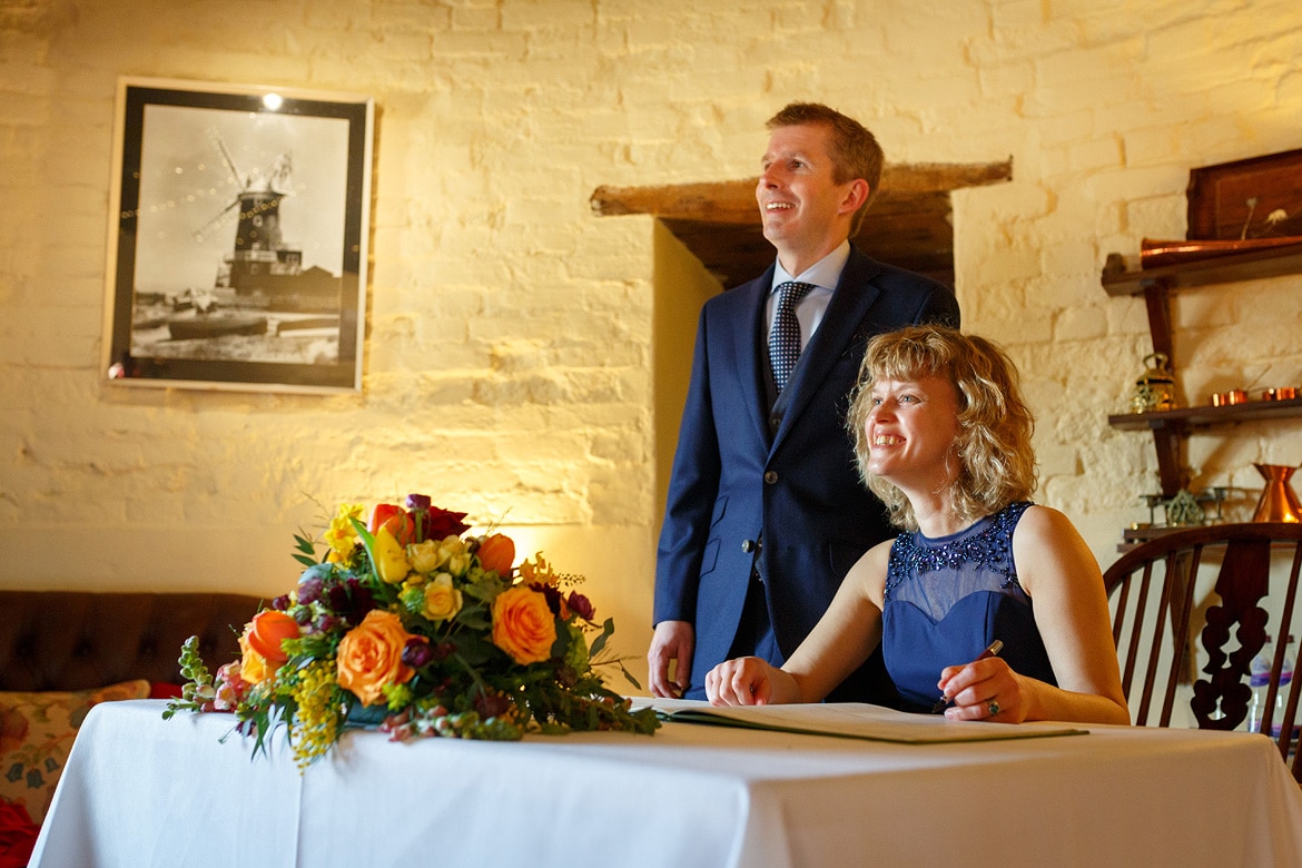 bride and groom pose for guests at their cley windmill wedding