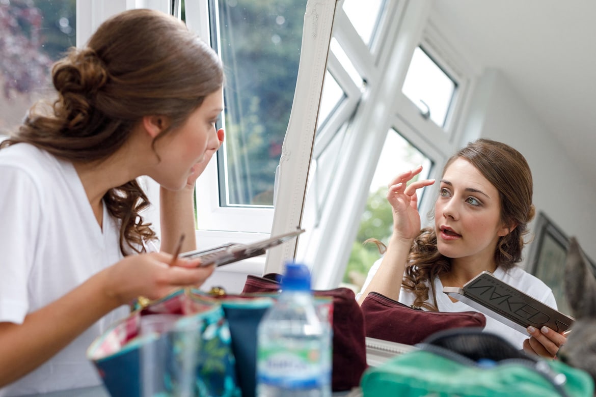 the bride applies her makeup in the mirror