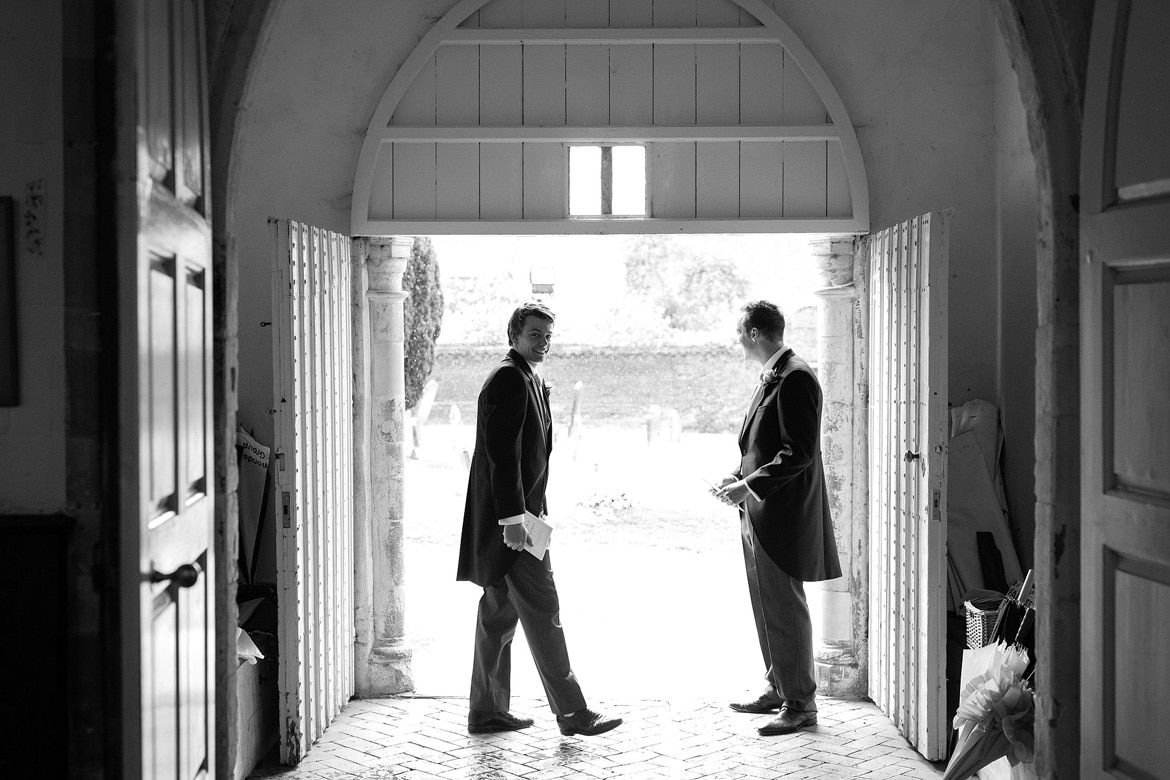 groomsmen shelter from the rain in the church porch