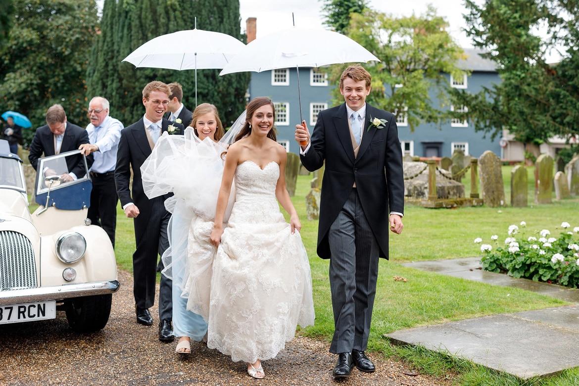 the bride walks through the rain into her framlingham wedding