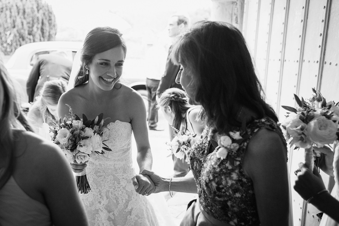 the bride is greeted by her mother in the church porch