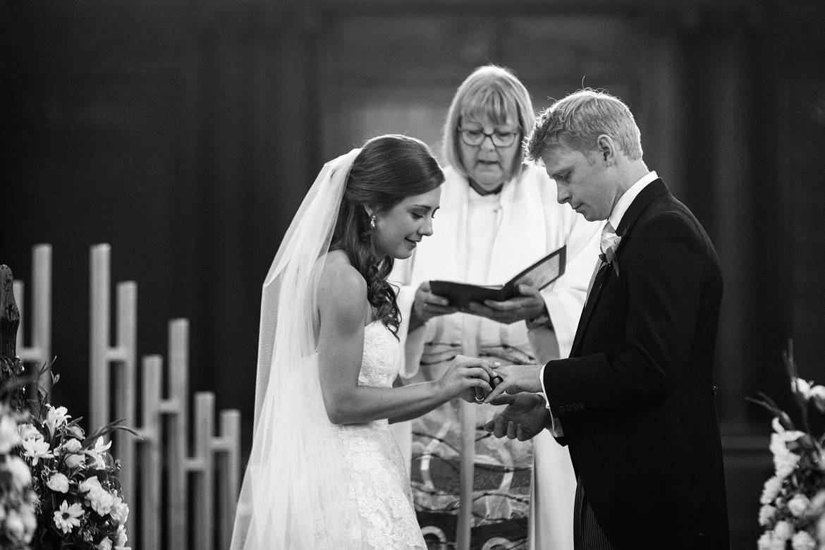 bride and groom exchange rings in framlingham church