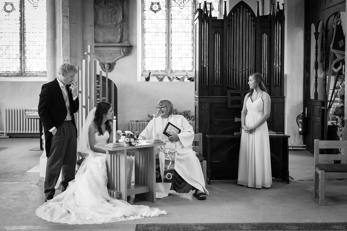 bride and groom sign the register in framlingham church