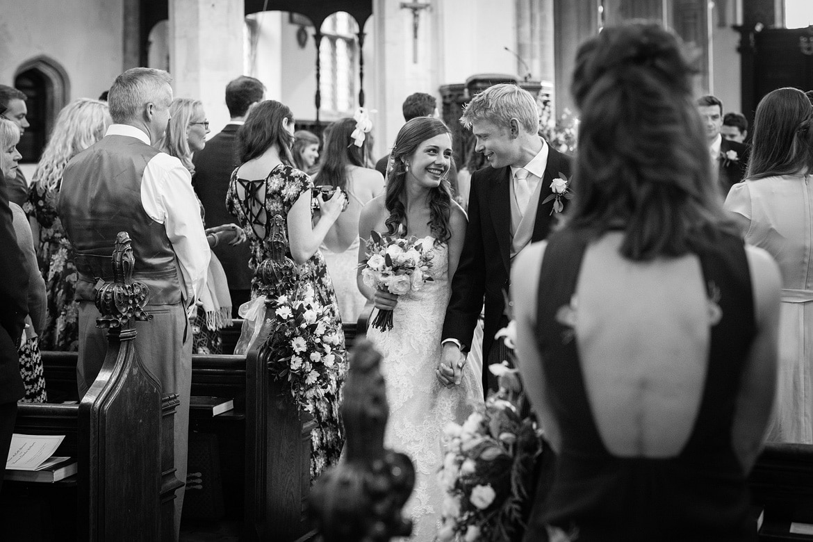 bride a groom smile as they walk down the aisle