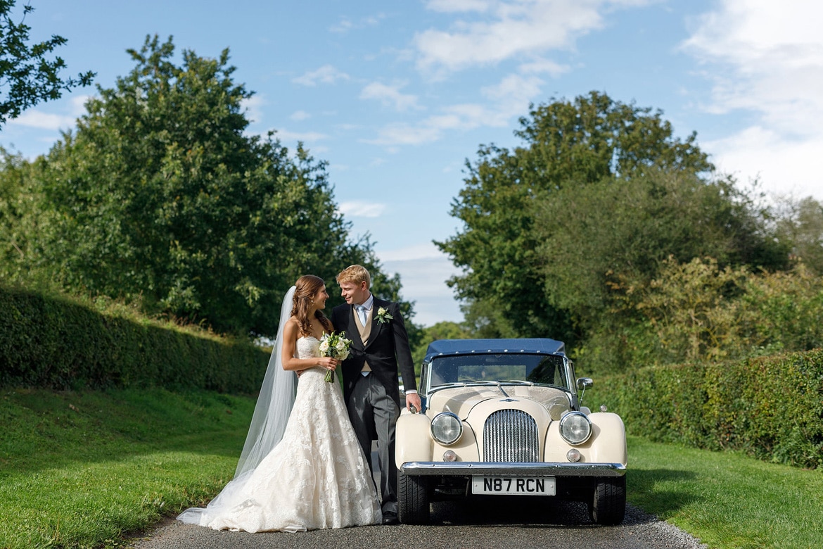 tom and anna pose with their vintage morgan wedding car